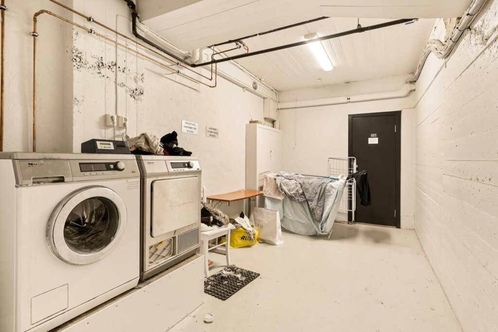 Spacious laundry room featuring washing machine and dryer with visible piping.